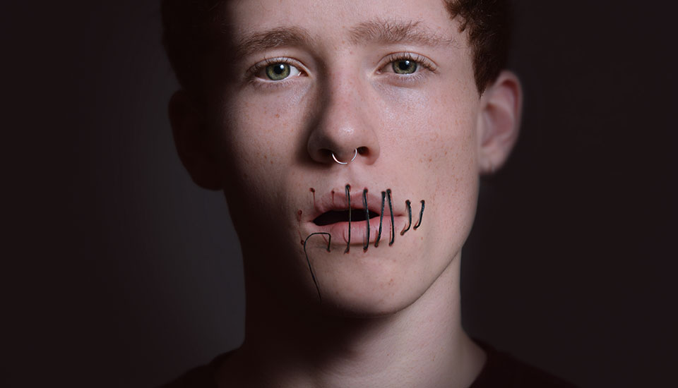 young lad with mouth sewn up